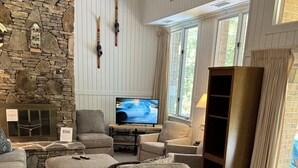 Un salón acogedor con pared de piedra, un televisor y un cartel que dice 'RELAX'.