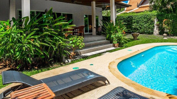 Un edificio moderno con piscina, sillas de descanso y un patio cubierto.
