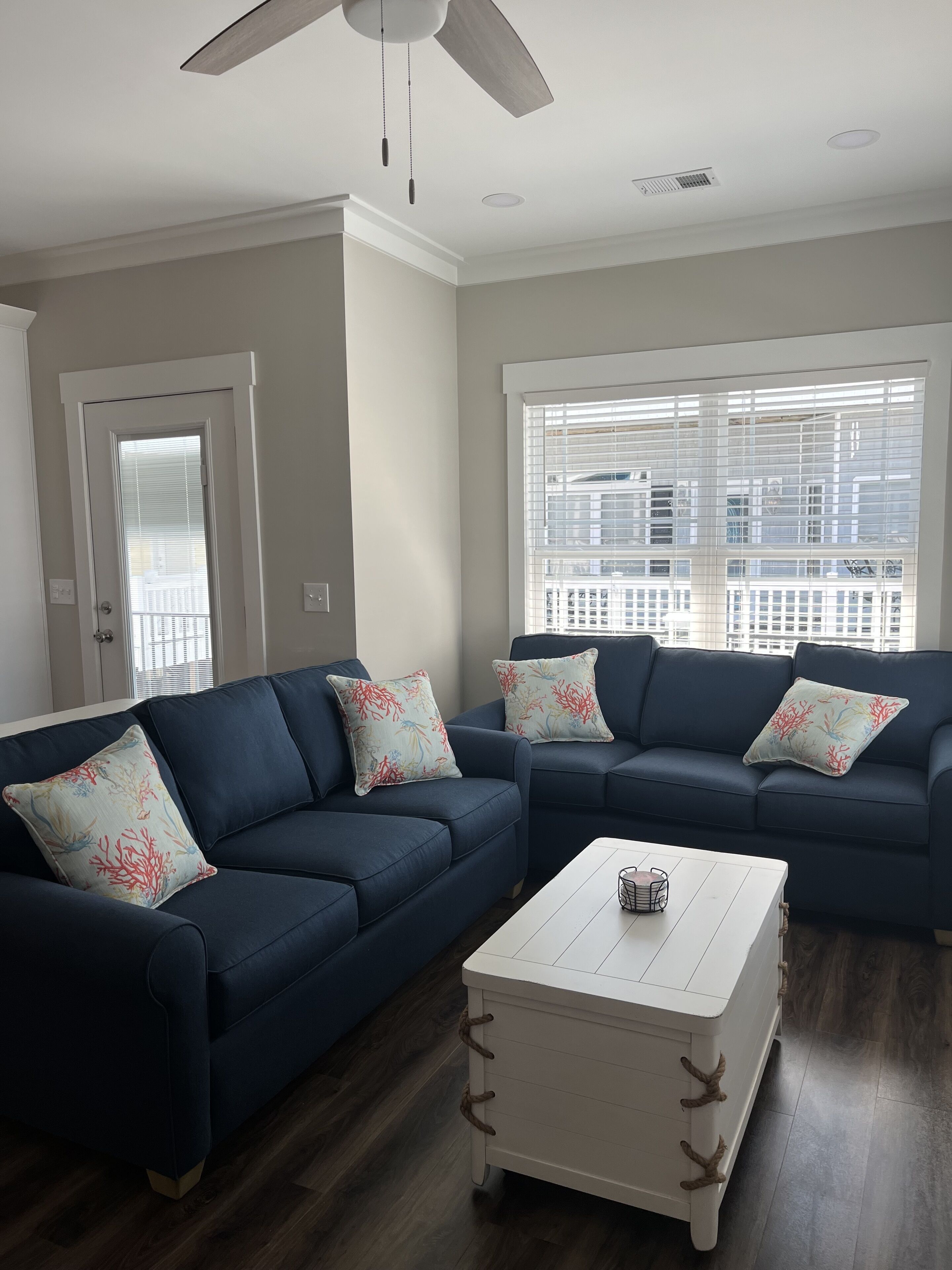 A living room with two dark blue sofas, white coffee table, and decorative pillows.