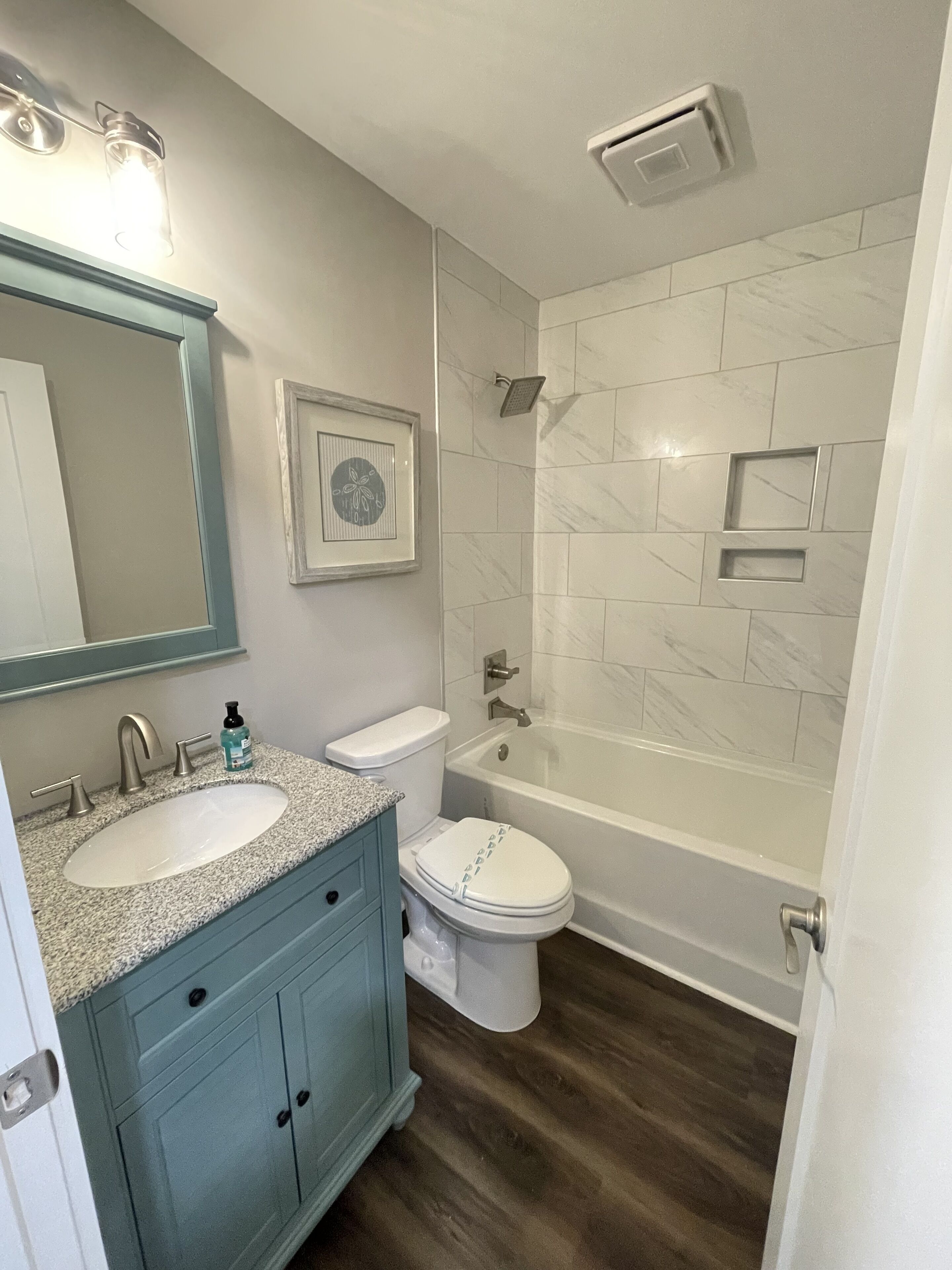 A bathroom with a sink, vanity, toilet, and bathtub.