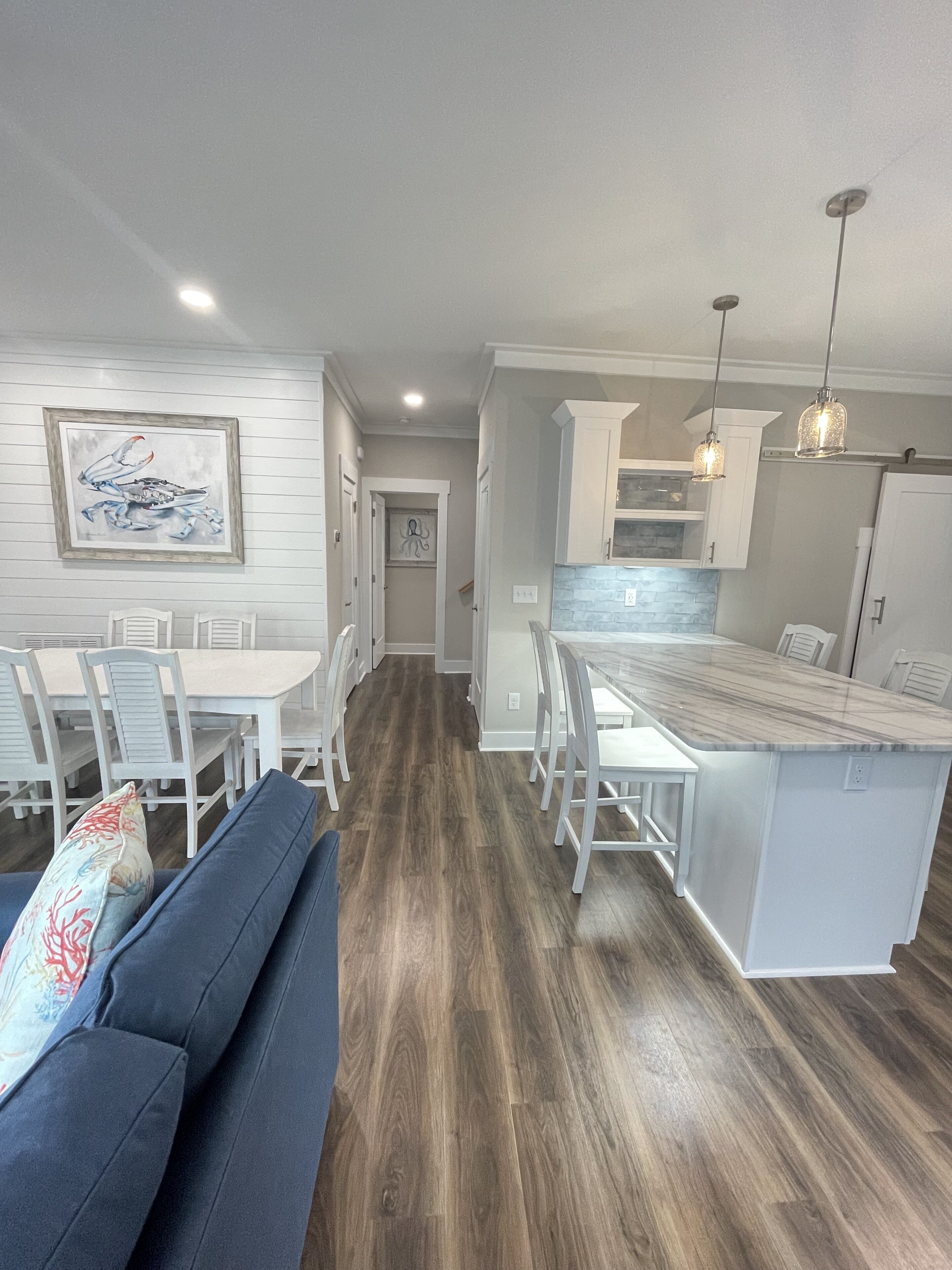 A modern kitchen with white cabinetry, a marble countertop island, and pendant lighting.