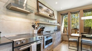 A modern kitchen with stainless steel appliances, wooden cabinets, and a dining area with a table and chairs.