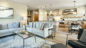 A modern living room with a sofa, coffee table, and a dining area with chairs and a table.