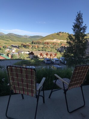 Relax in a serene outdoor seating area with scenic views of rolling hills and a body of water.