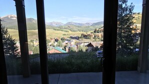 A view from a room with large windows overlooking a valley with houses and mountains. - Remodeled ski in/ski out condo in Mt Crested Butte with incredible views! (Crested Butte)