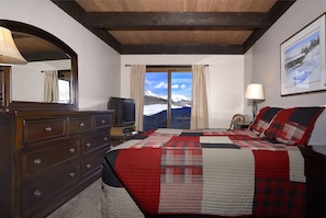 Relax in a cozy retreat with a traditional design, featuring a dresser, TV, and stunning mountain views.
