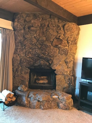 Cozy living room with a stone fireplace and entertainment unit, perfect for relaxing.