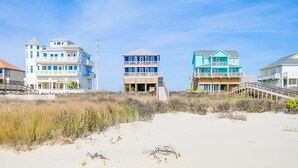 A beachfront property with a multi-story building featuring balconies and a beach access walkway.