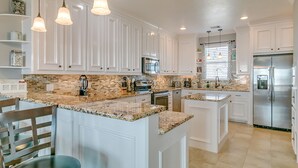 A spacious kitchen with white cabinetry, granite countertops, and stainless steel appliances.