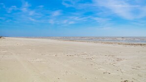A wide sandy beach with gentle waves and a clear blue sky.