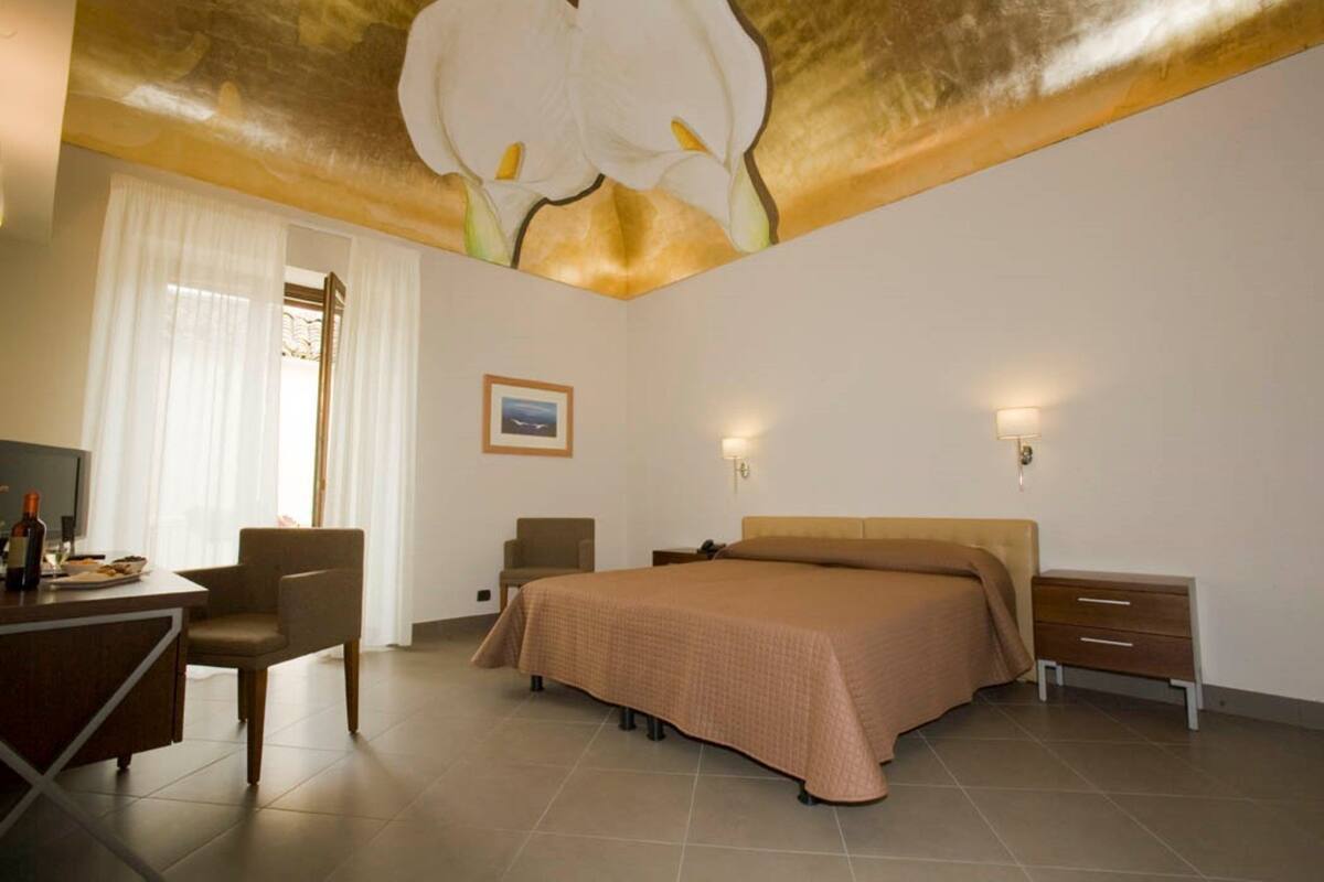 A hotel room with a bed, a desk, a chair, and a nightstand.