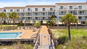 A hotel with multiple floors, outdoor pool, and palm trees. - Beachfront Condo - Complimentary Beach Chair Service - Mar-Oct (Panama City Beach)
