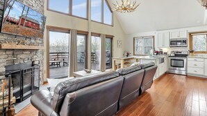 A spacious living area with a fireplace, a large window, and a kitchen with modern appliances.