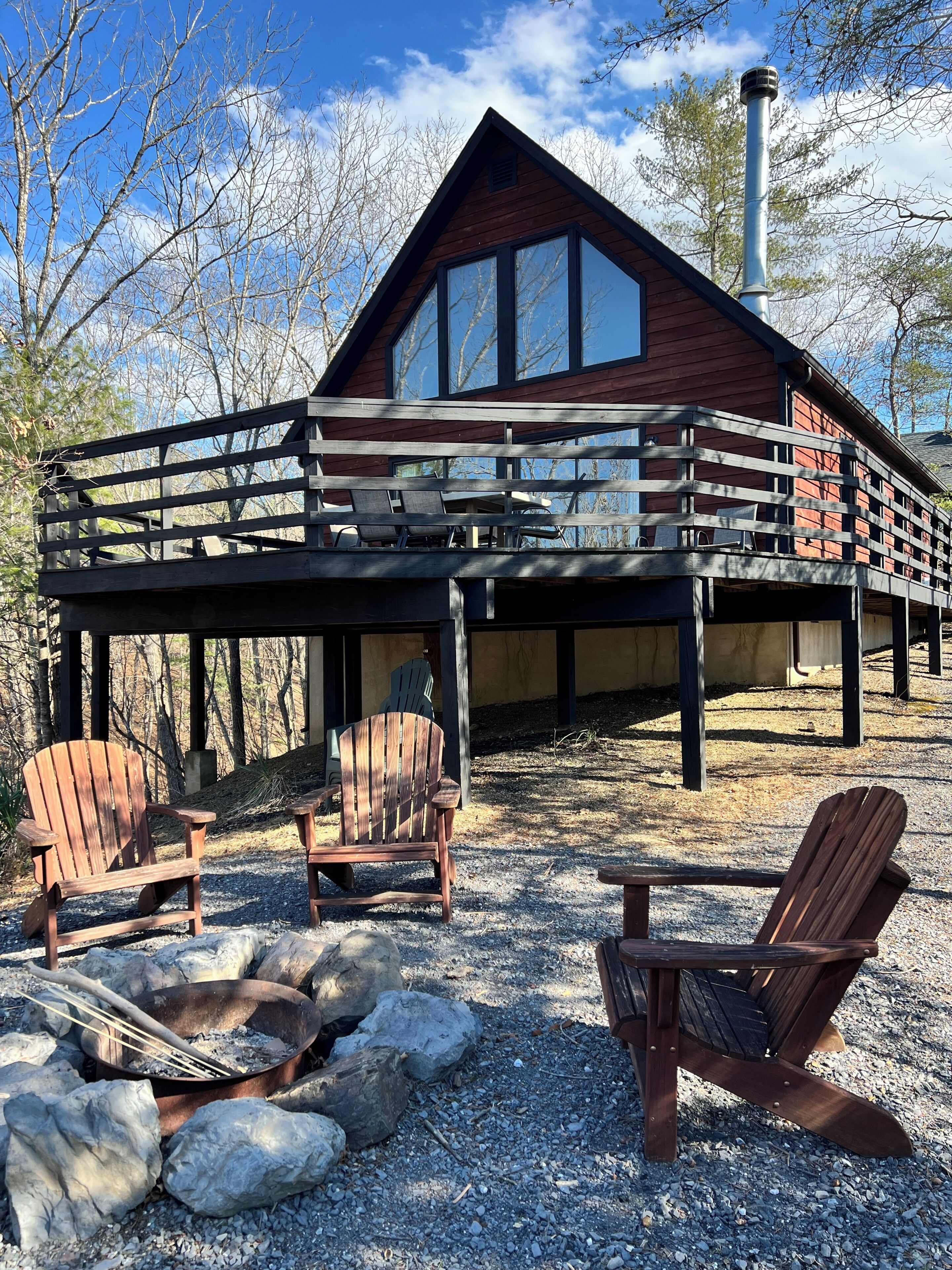 A cabin with a deck, outdoor seating, and a fire pit.
