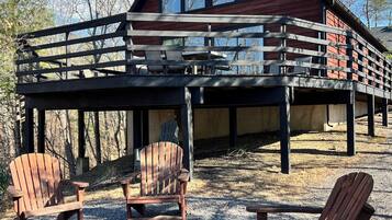 A cabin with a deck, outdoor seating, and a fire pit.