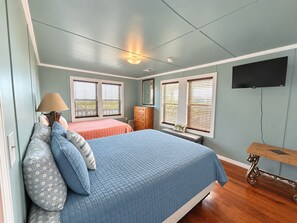 Une chambre à coucher avec un lit, une commode et un téléviseur.