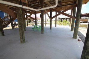 Un pavillon ouvert doté d’un sol en béton, de tables de pique-nique vertes et de piliers en bois.