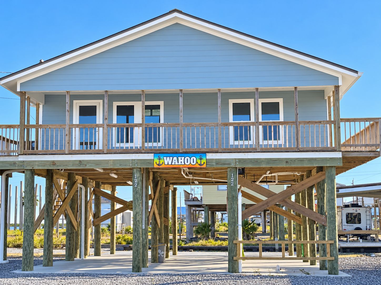 A two-story wooden structure with a balcony, supported by wooden stilts, and a sign reading 'WAHOO'.