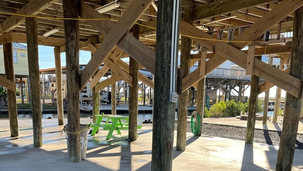 Eine offene Holzkonstruktion mit Betonboden, möglicherweise eine überdachte Fläche oder Terrasse.