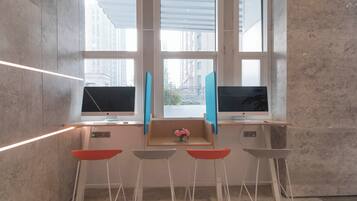 Un espacio de trabajo moderno con dos monitores, un teclado y un ratón sobre un escritorio de madera. Hay cuatro sillas y un florero con flores en el escritorio.