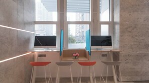 A modern workspace with two monitors, a keyboard, and a mouse on a wooden desk. There are four chairs and a vase with flowers on the desk. - Holiday Inn Express Liyang Huafu by IHG (Changzhou)