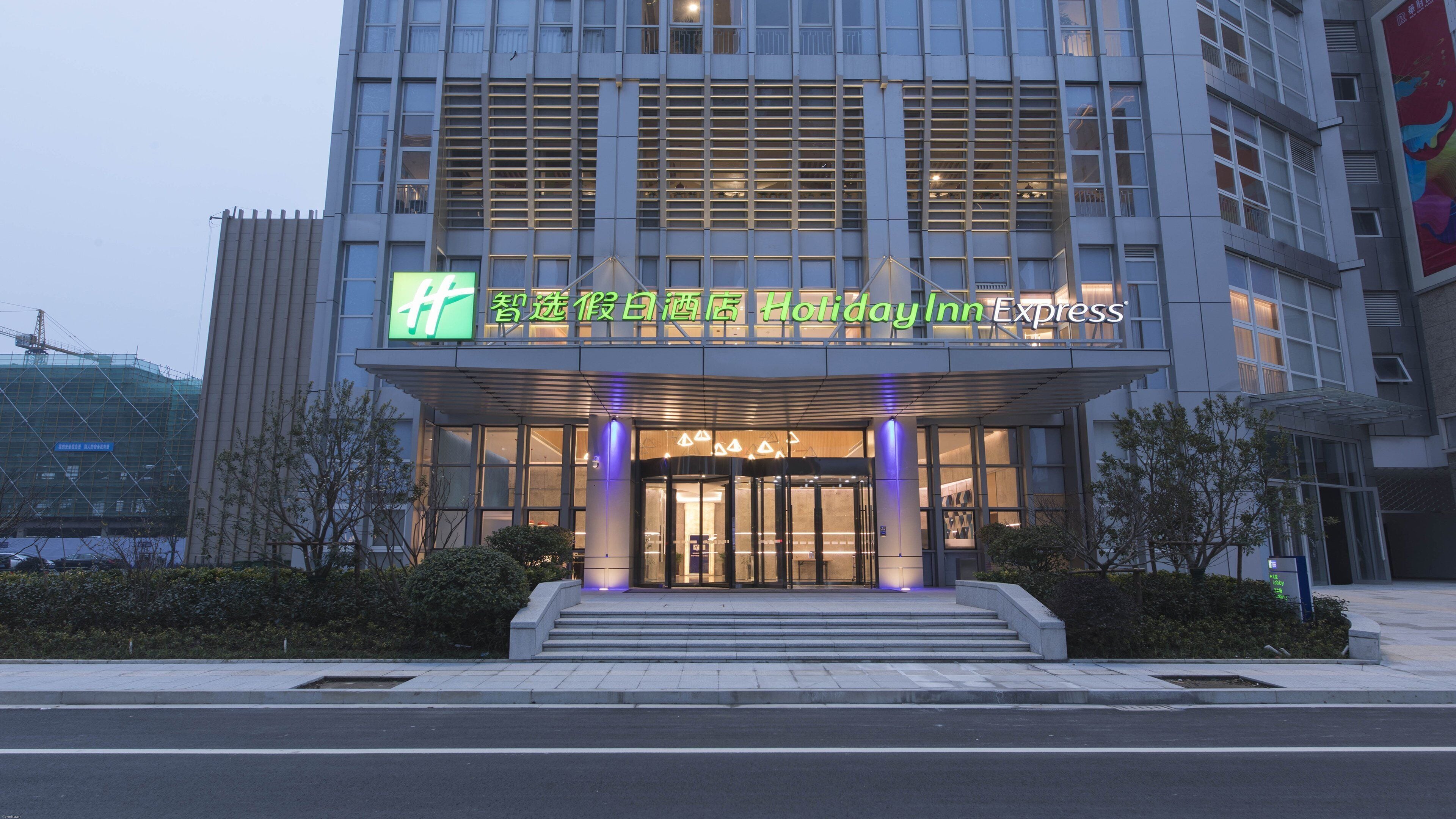 L’entrée d’un hôtel, avec une façade moderne, un escalier bien visible menant à l’entrée et une vue dégagée sur les environs.