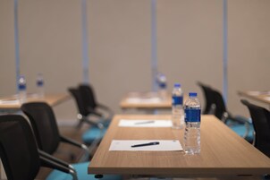 Una sala de conferencias con mesas, sillas, botellas de agua y documentos.