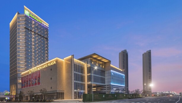 A modern hotel with a prominent 'Holiday Inn Express' sign, a 'Rich Gate Plaza' entrance, and adjacent high-rise buildings. - Holiday Inn Express Liyang Huafu by IHG (Changzhou)