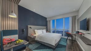 A modern hotel room with a large bed, a desk, a chair, a TV, and a balcony with a city view. - Holiday Inn Express Liyang Huafu by IHG (Changzhou)