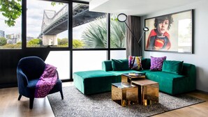 A modern living room with a green sofa, a blue armchair, and a coffee table. - Crystalbrook Vincent (Brisbane)