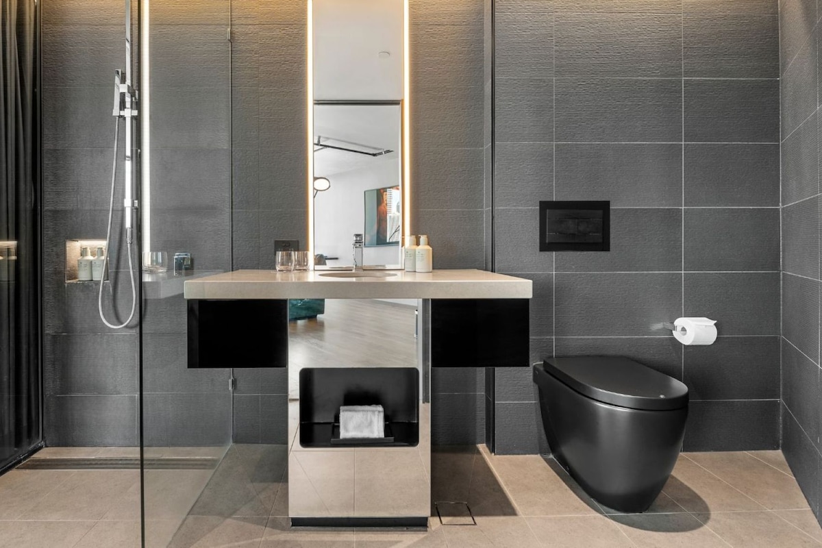 A modern bathroom with a glass shower enclosure, a sink with a mirror, and a toilet.