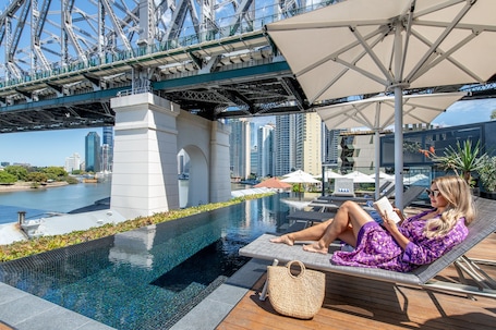 Una piscina al aire libre, sombrillas, sillones reclinables de piscina