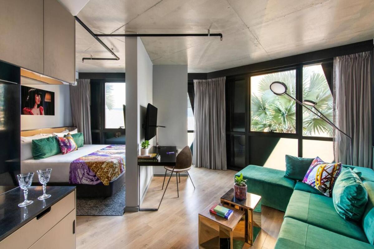 Une chambre d’hôtel moderne équipée d’un lit, d’un canapé, d’un bureau et d’une grande fenêtre avec des rideaux.
