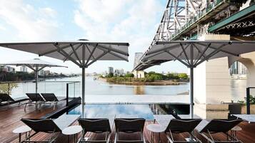 Una piscina al aire libre, sombrillas, sillones reclinables de piscina