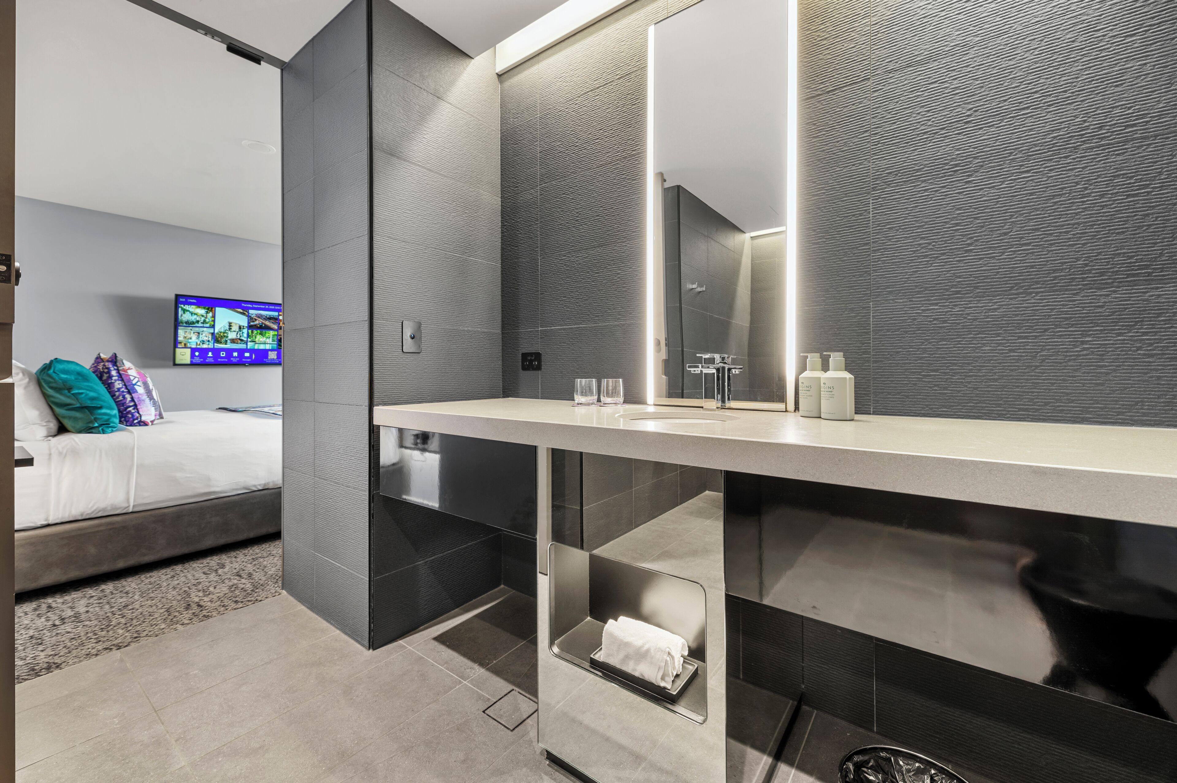 A modern bathroom with a large mirror, a sink, and a towel rack.