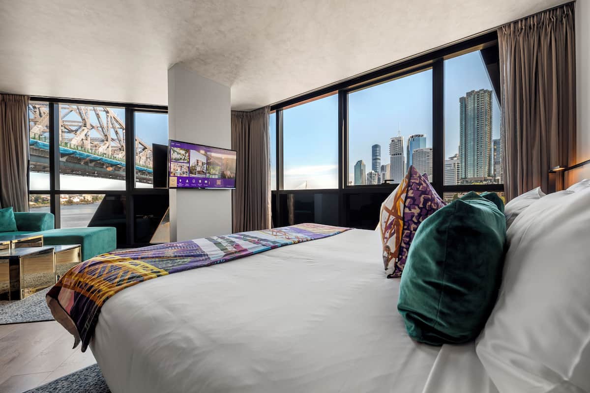Une chambre d’hôtel avec un grand lit, une télévision, un bureau et une vue sur le paysage urbain.