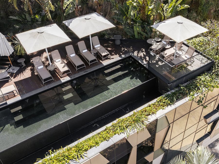 Una piscina al aire libre, sombrillas, sillones reclinables de piscina