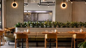 A restaurant with a long counter, wooden chairs, and a central seating area with a cushioned bench. - Crystalbrook Vincent (Brisbane)