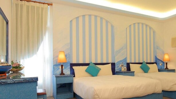 Habitación de hotel con dos camas, decoración de pared a rayas y lámparas de noche.