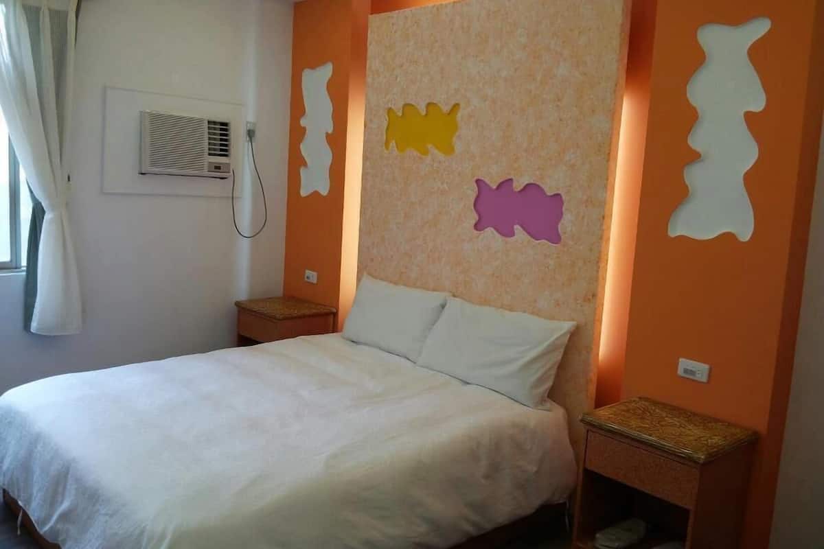 A bedroom with a bed, nightstands, and a wall with cut-out shapes.