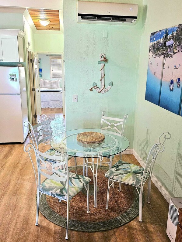 Un comedor con una mesa de vidrio y sillas, un mantel tejido y un adorno anclado a la pared.