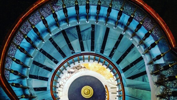 Eine Wendeltreppe mit einer zentralen Säule und Geländern.