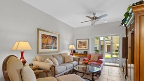 A living room with a sofa, chairs, a coffee table, and two lamps. There is a ceiling fan and a door leading to an outdoor area. - Fantastic Townhome with Club Access, Steps from Walmart, and Close to Disney! (Kissimmee)