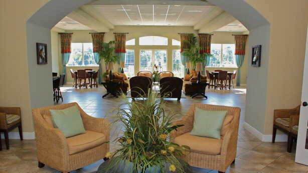 A spacious lobby with wicker furniture, a central plant, and large windows offering a view. - Fantastic Townhome with Club Access, Steps from Walmart, and Close to Disney! (Kissimmee)