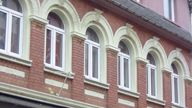 A multi-story building with a row of arched windows and a balcony. - Falkenstein Aparts (Falkenstein/Vogtl.)