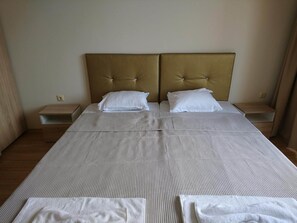 Ein Doppelbett mit gestreifter Bettdecke, zwei weiße Kissen und ein gepolsterter Kopfteil. Es gibt zwei Nachttische mit Lampen.