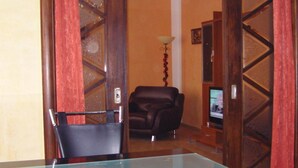 A room with a glass table, a leather chair, a sofa, and a television. - Falkenstein Aparts (Falkenstein/Vogtl.)