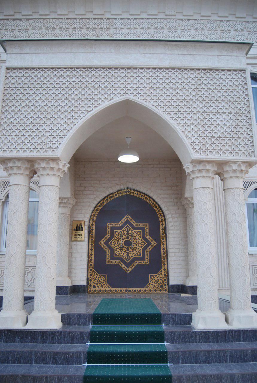 A building entrance with a large, ornate door, a sign indicating it's a hotel, and a staircase leading up to it.