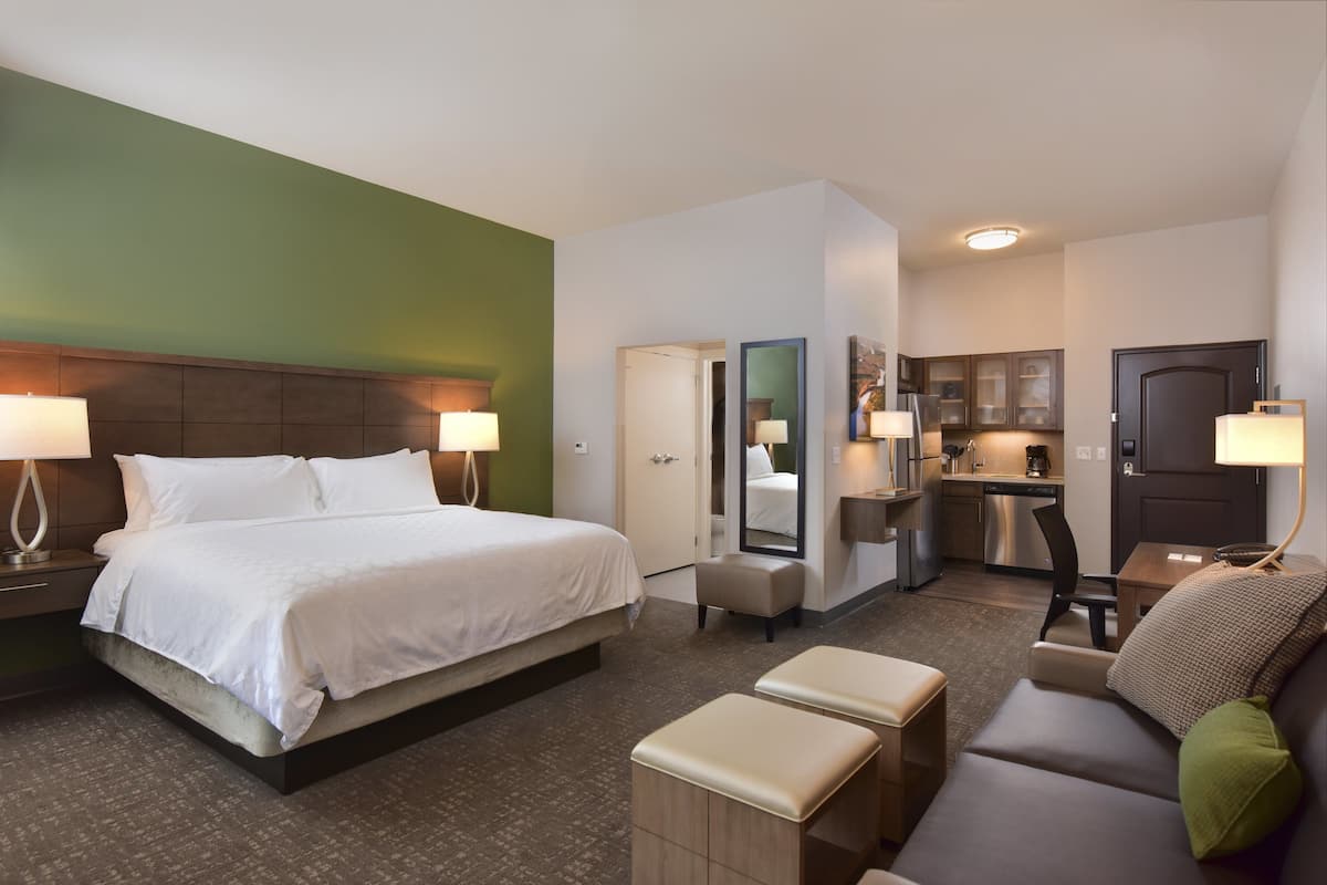 Ein Hotelzimmer mit einem großen Bett, einer Couch, einem kleinen Tisch, einer Küchenzeile und einem Badezimmer.