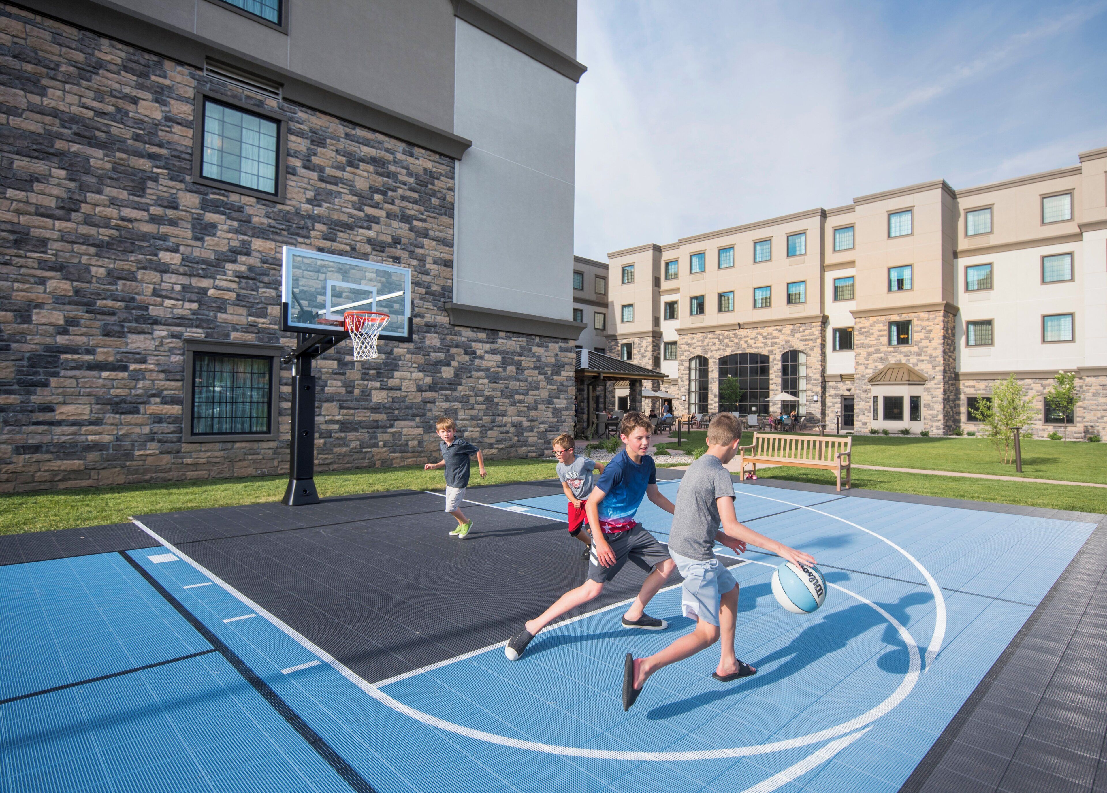 Un terrain de basket en plein air, avec un bâtiment en arrière-plan.